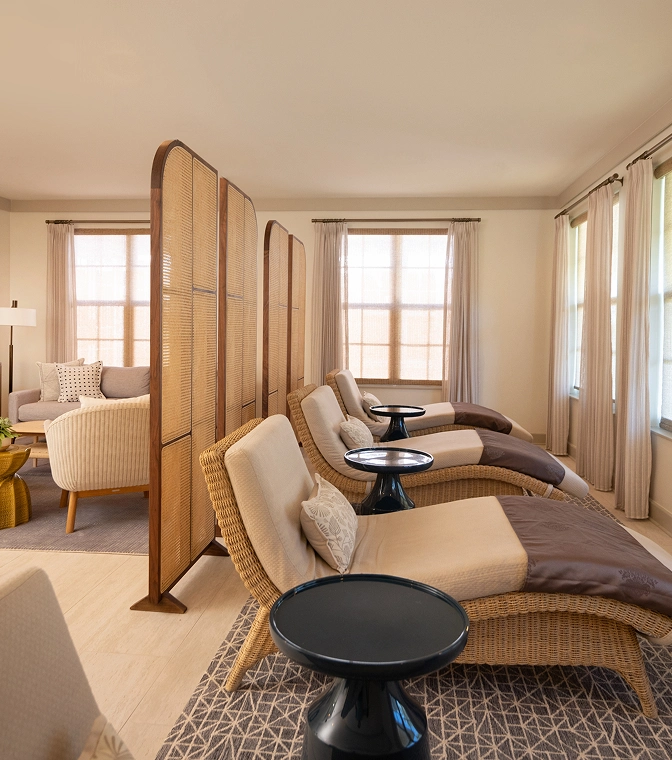 Spa relaxation room with wicker lounge chairs, woven privacy screens, and a serene, neutral-toned seating area.