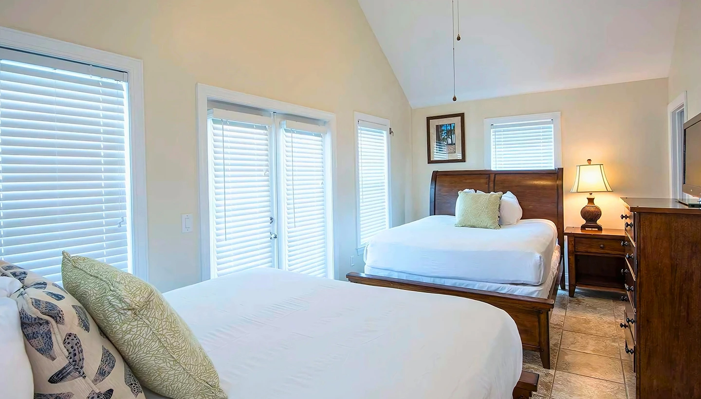 Bright 3-bedroom home at Hawks Cay with two queen beds, vaulted ceilings, and large windows with white blinds.