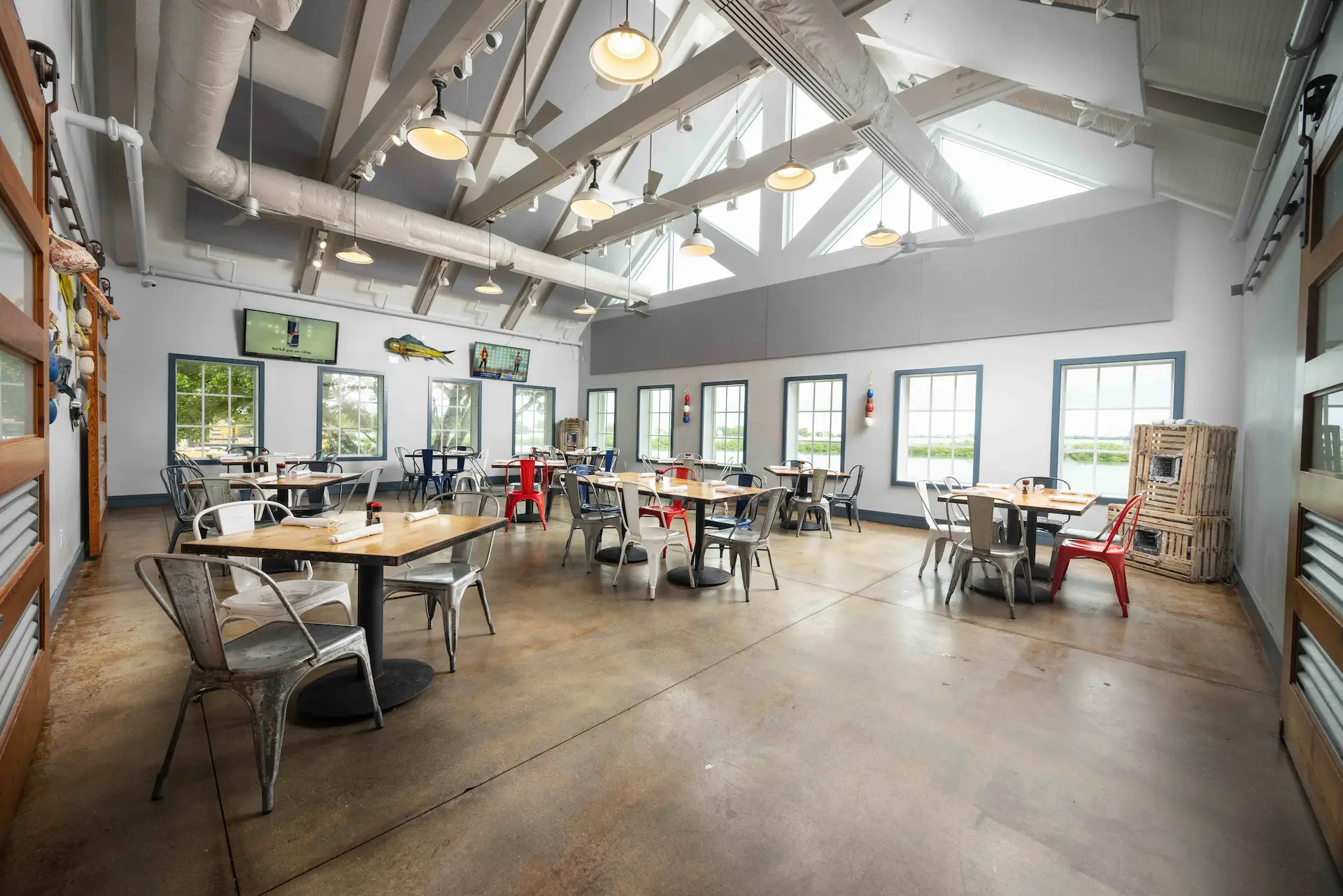 Spacious Angler & Ale dining room with vaulted ceilings, industrial lighting, and colorful metal chairs.