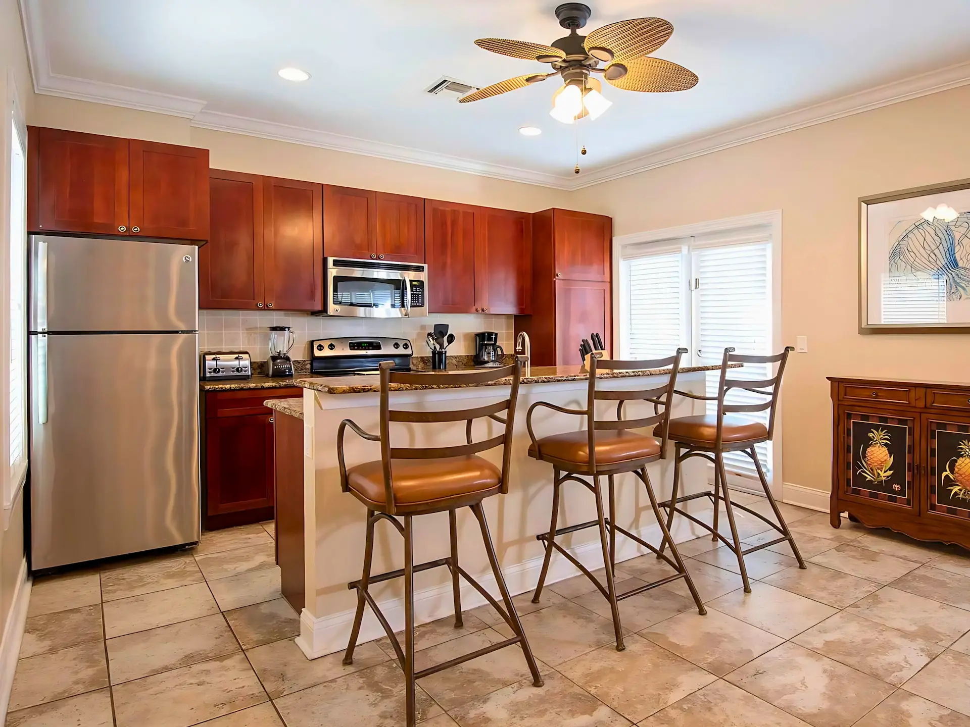 Modern Hawks Cay villa kitchen with dark wood cabinets, stainless steel appliances, and a breakfast bar with three stools.