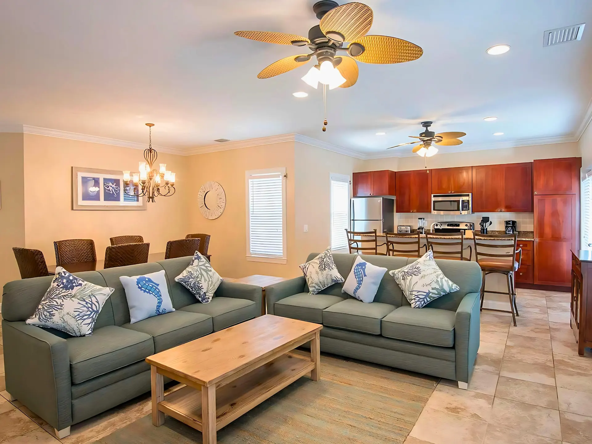 Open-concept Hawks Cay villa featuring two teal sofas with coastal pillows, a dining area, and a modern kitchen.