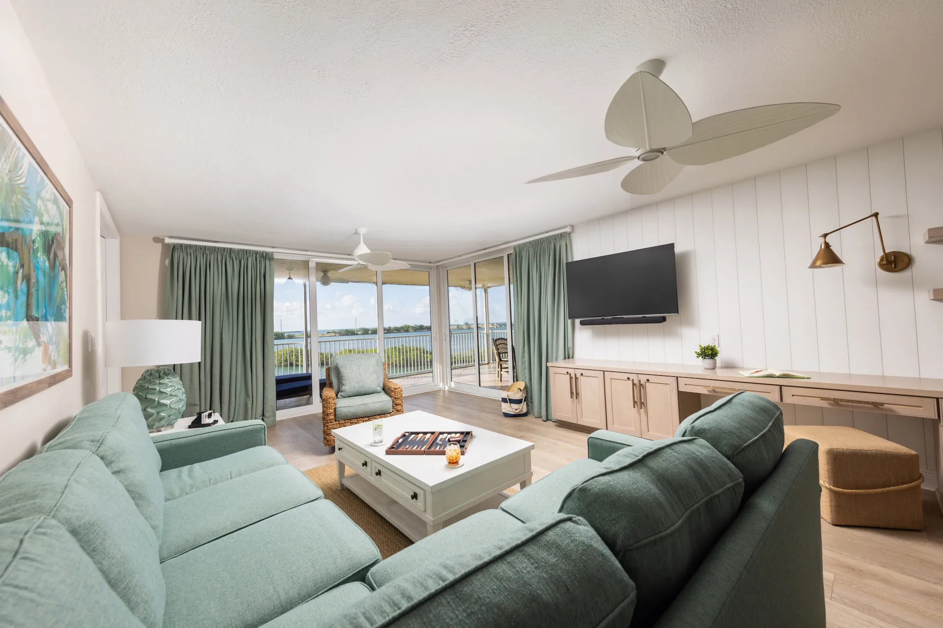 Modern single-level premium Hawks Cay villa with teal sofas, a white coffee table, and expansive waterfront balcony views.