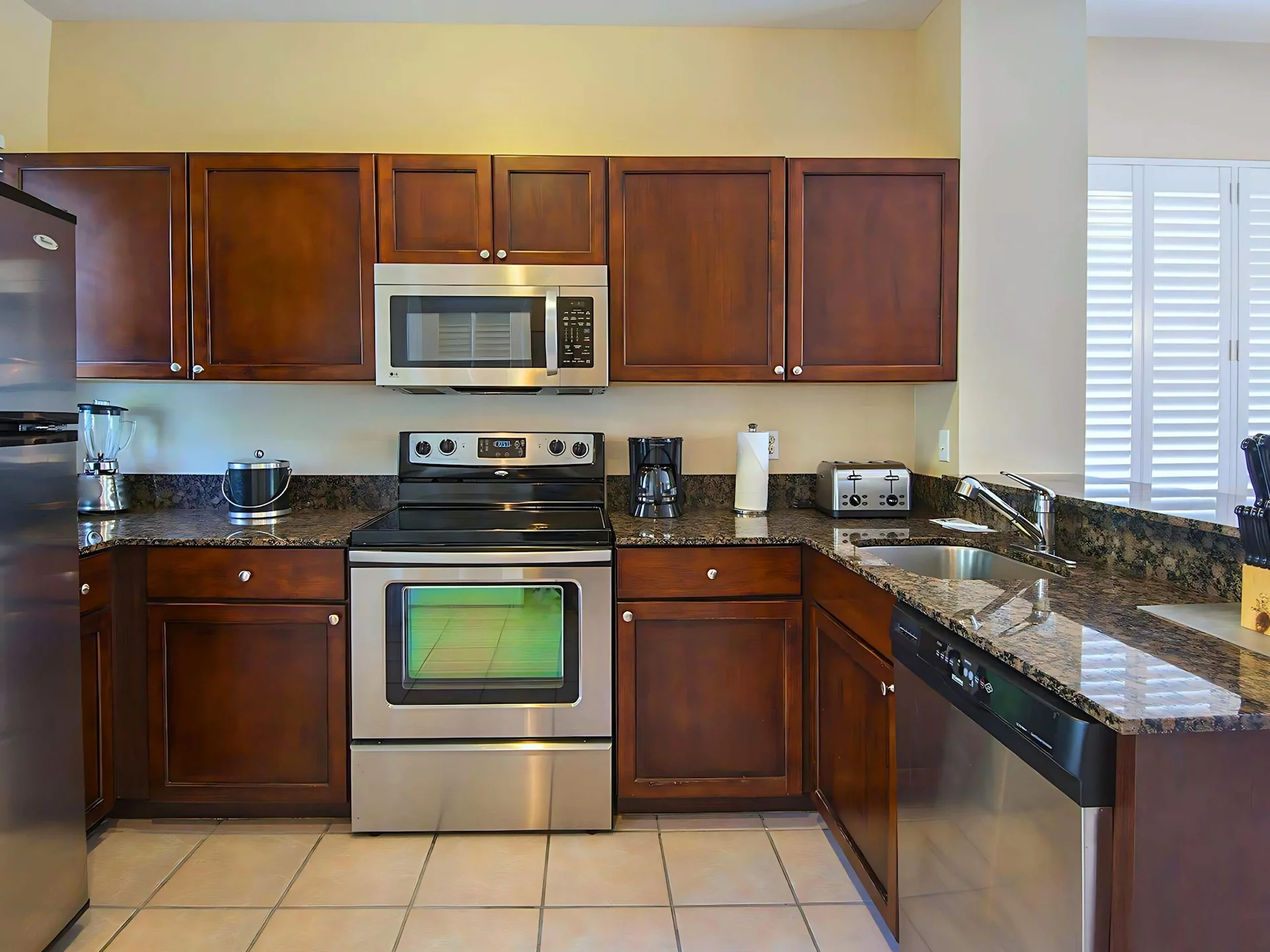 Modern villa kitchen with dark wood cabinets, granite countertops, and stainless steel appliances.