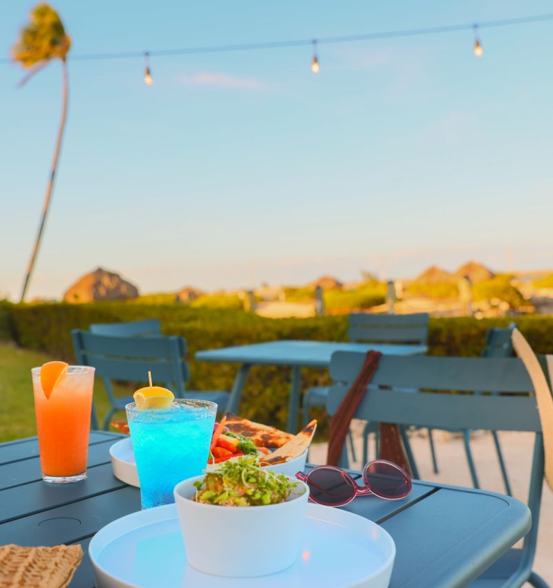 colorful cocktails on a table with a pair of sunglasses and some lite bites
