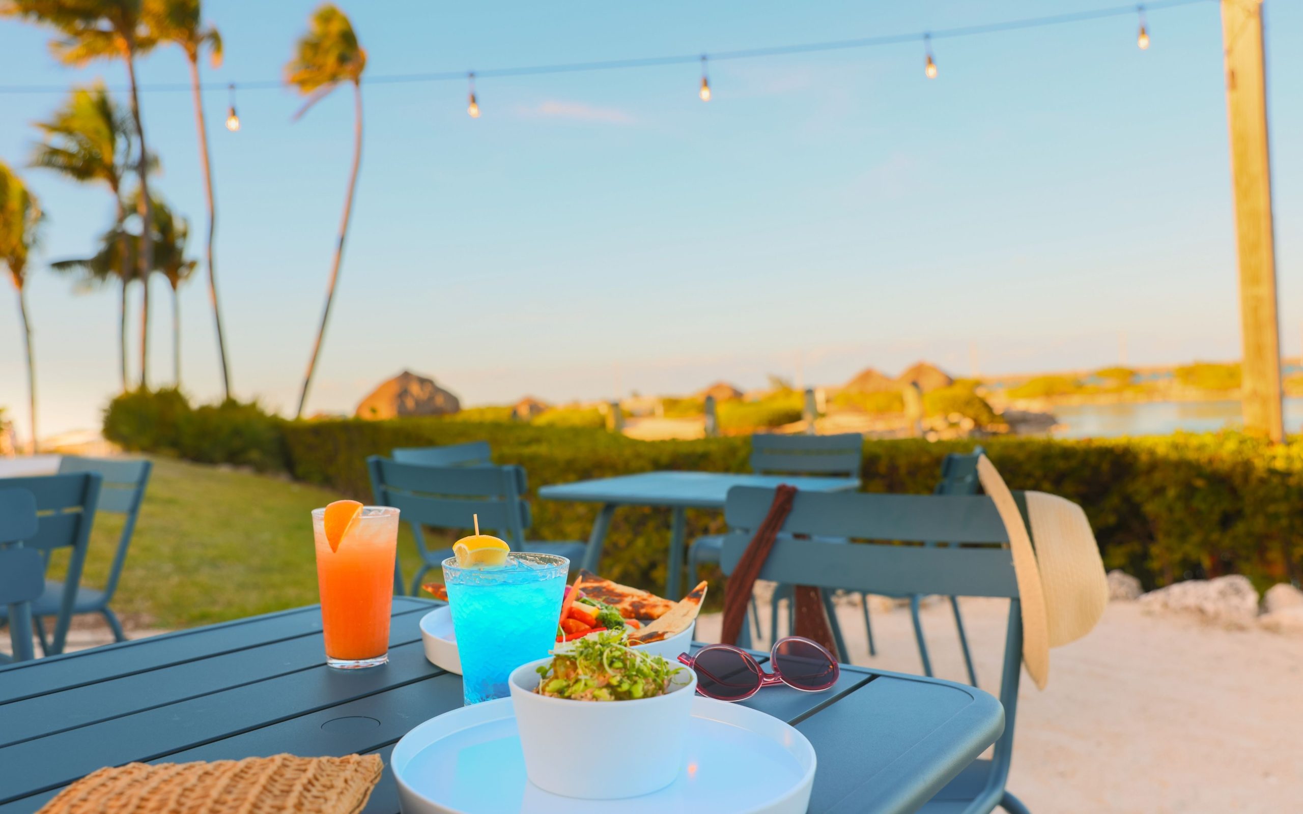 colorful cocktails on a table with a pair of sunglasses and some lite bites