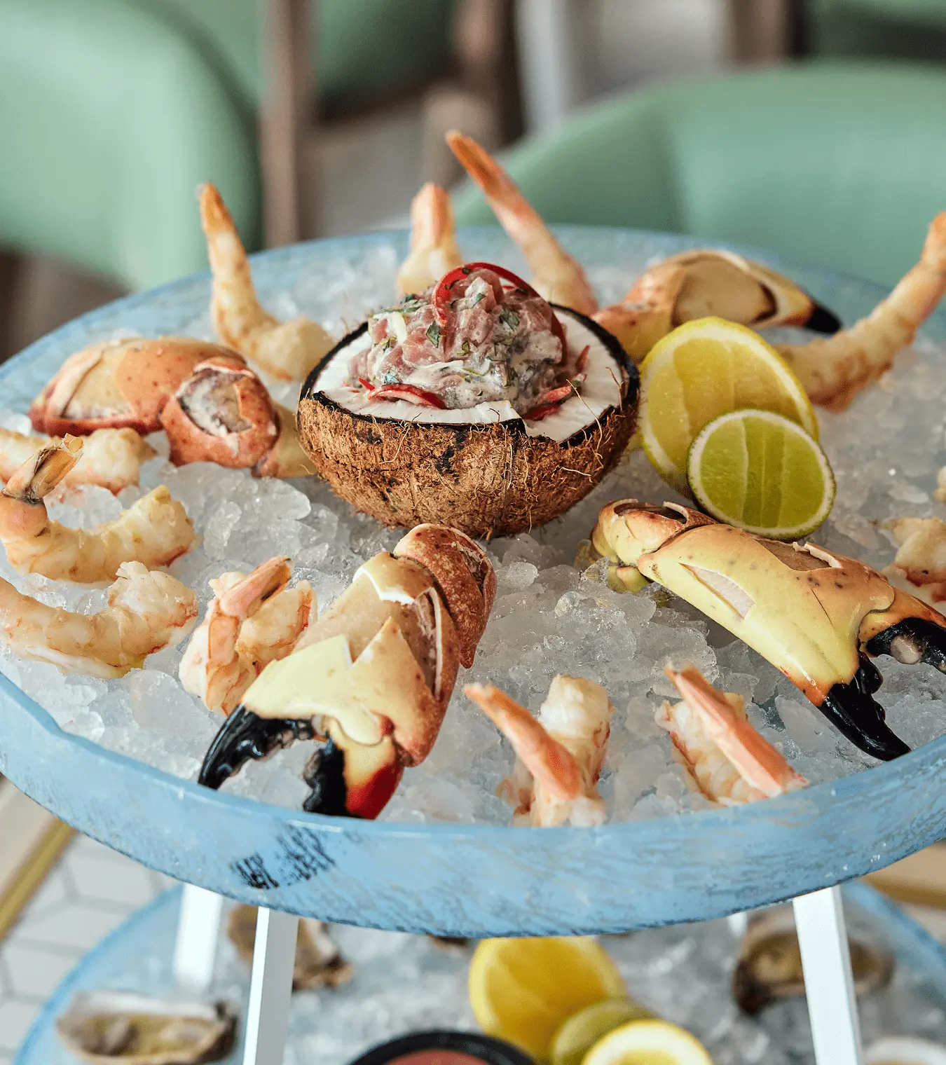 Chilled seafood platter with crab claws, shrimp, and tuna ceviche served in a coconut shell on ice.