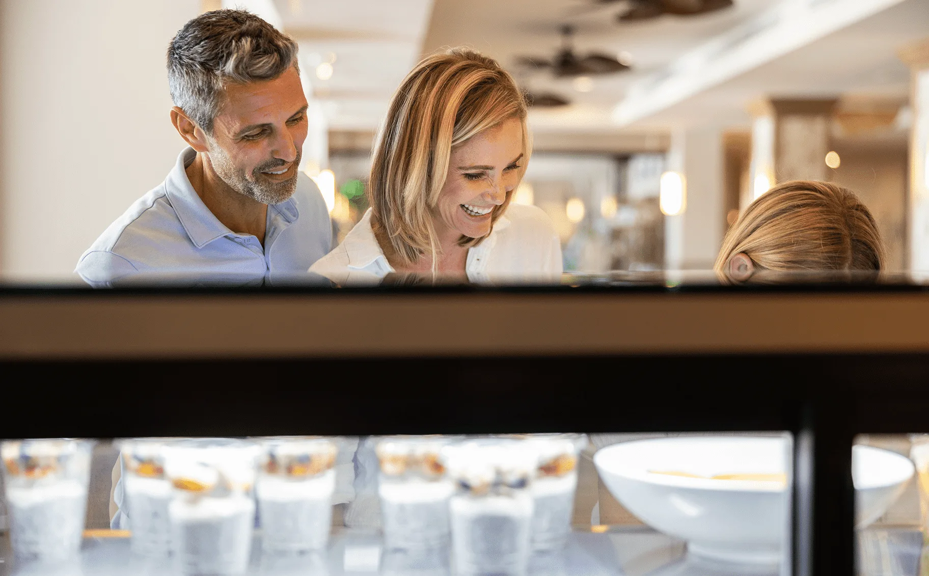 A smiling couple and their child looking at a selection of yogurt parfaits and breakfast items at Hawks Cay.