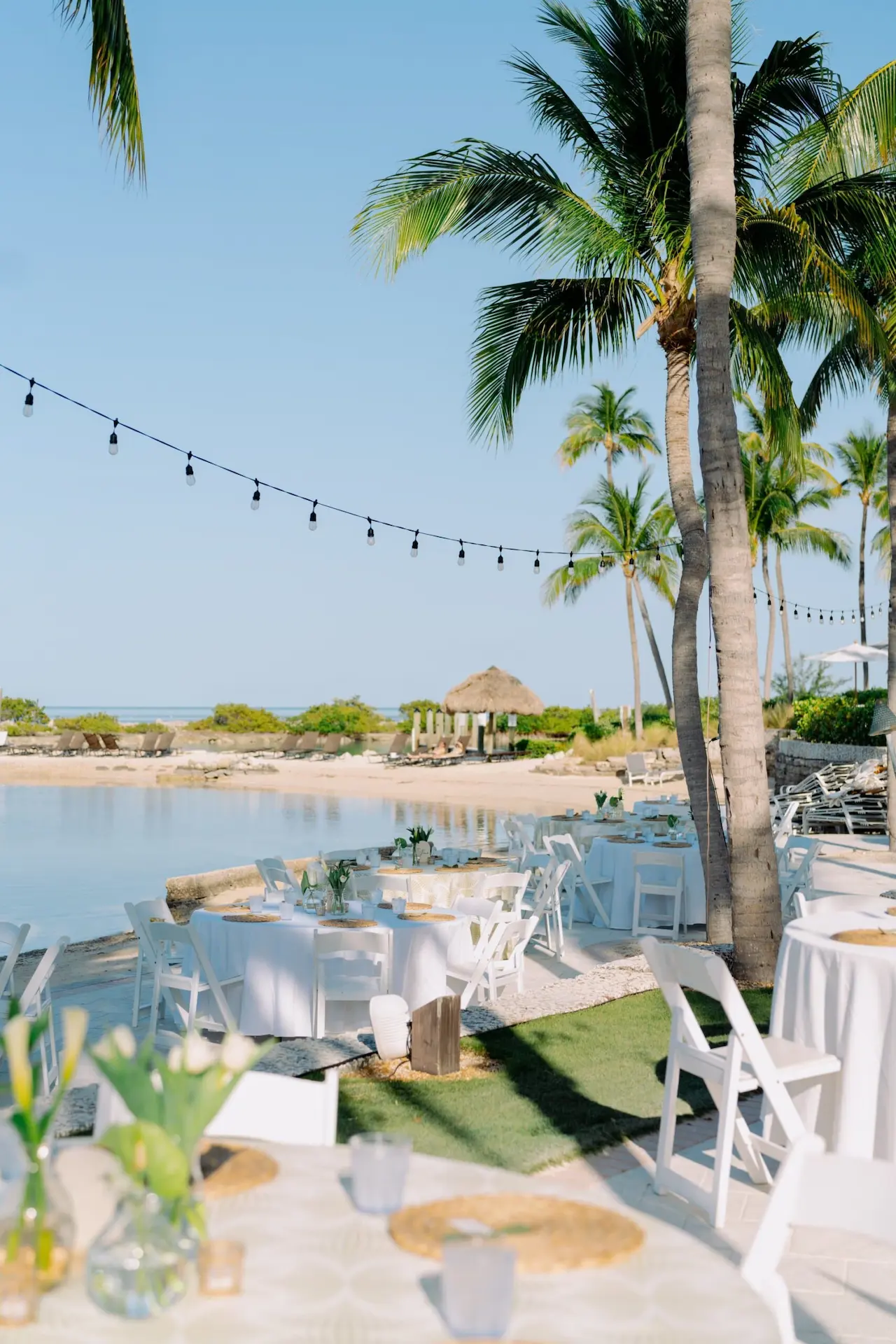 Elegant outdoor wedding reception setup at Hawks Cay with white-clothed tables along a tropical saltwater lagoon.