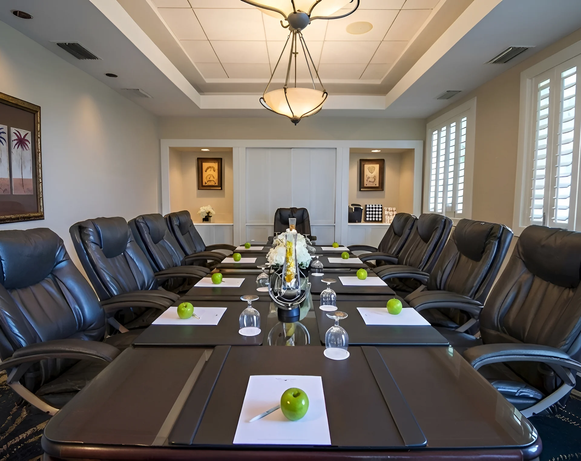 Conference room at Hawks Cay set for a meeting, with executive chairs, notepads, green apples, and floral centerpiece.