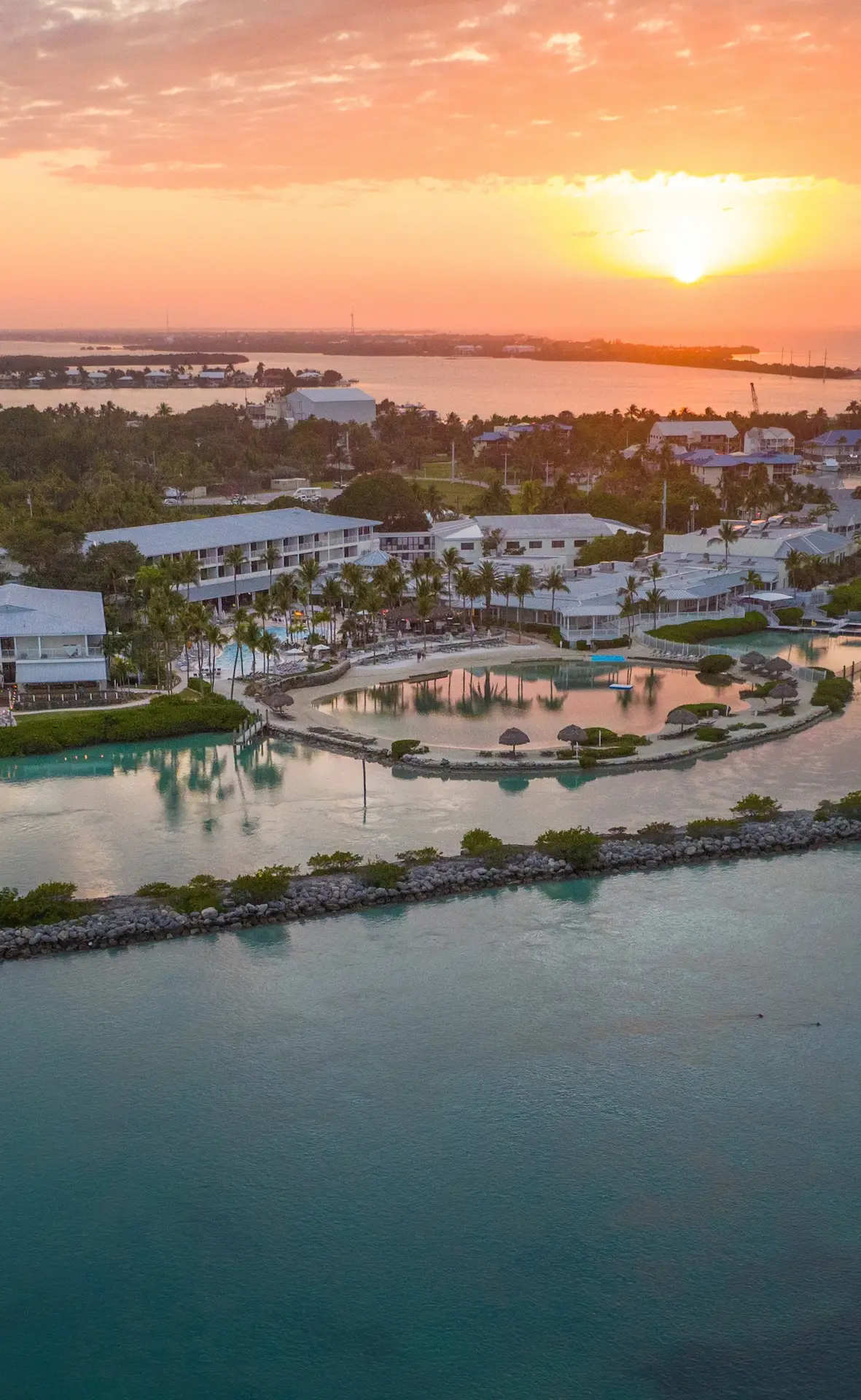 Sunset view over Hawks Cay Resort with palm trees, lagoon, and ocean horizon glowing in warm light.
