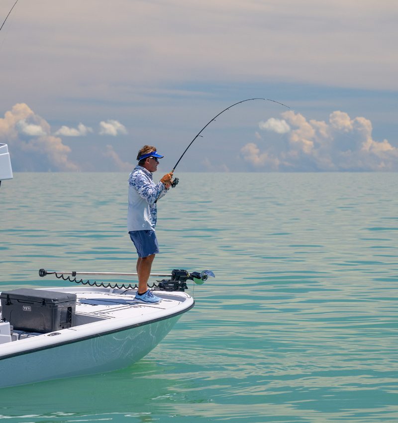 man on a boat catching a a fish on a center console boat