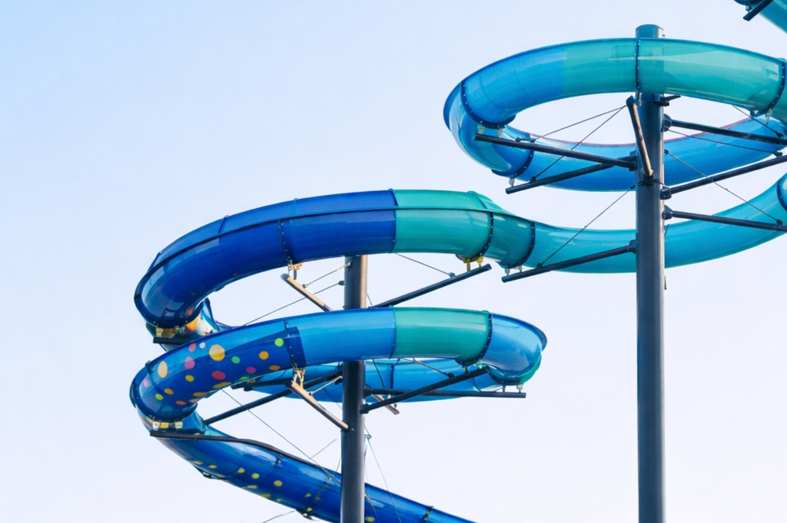 Close-up view of twisting blue and turquoise waterslides rising against a clear sky at Coral Cay Adventure Park, capturing the playful energy and vibrant design of the resort’s signature attractions.